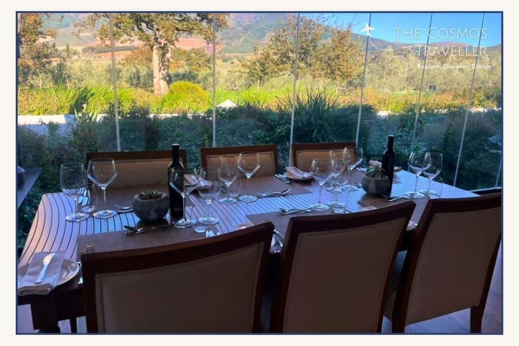 A table is laid for 6 people in front to a lush garden.