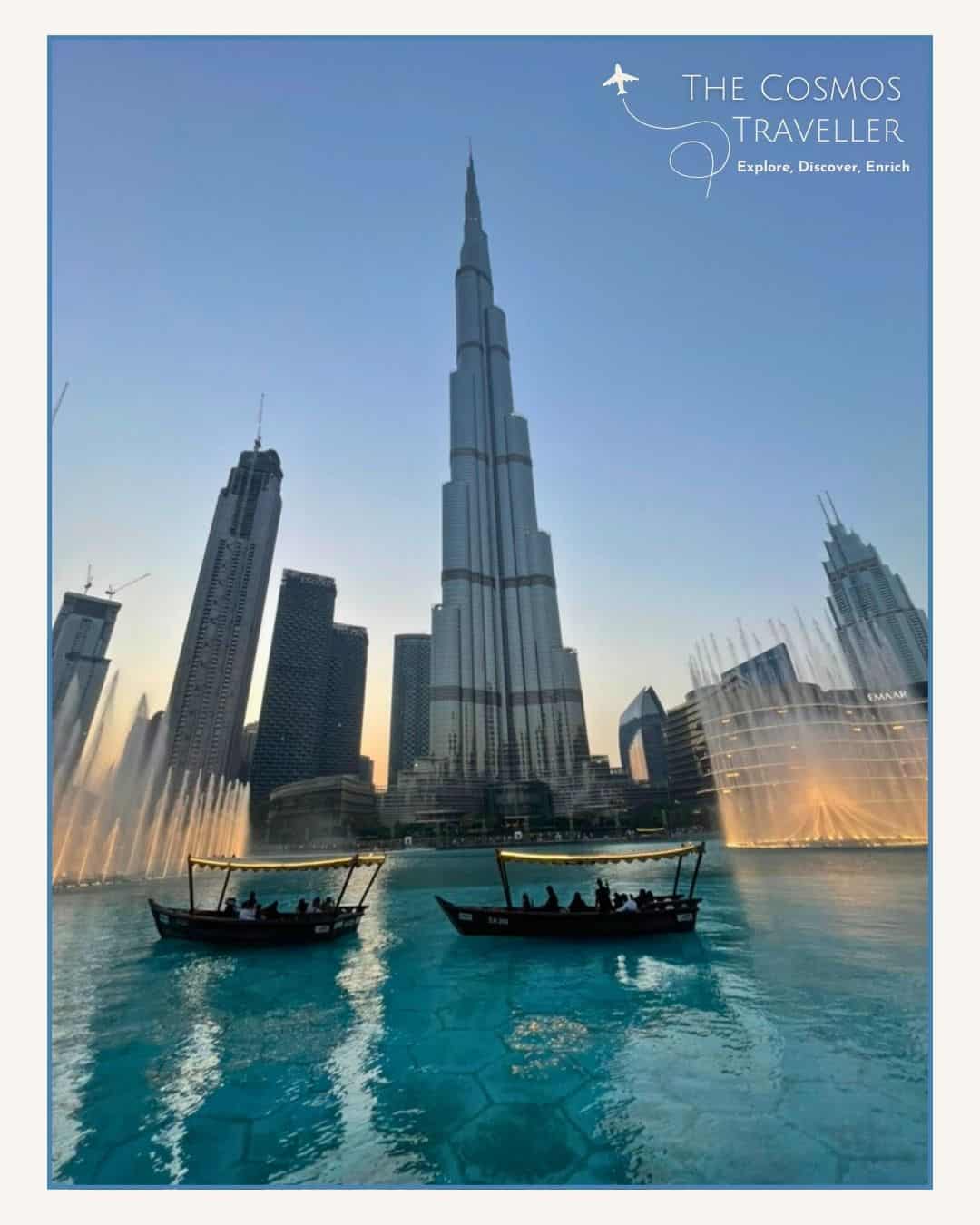 Burj Khalifa at sunset viewed across the lake with small boats in the foreground.