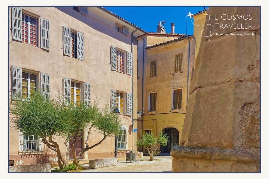 Beige stone buildings in a central square in Brignoles, Provence, with olive trees and a quiet village atmosphere.