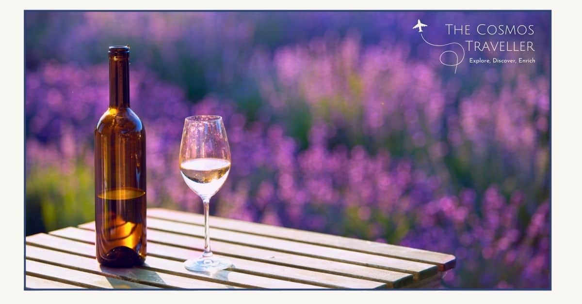 A bottle and glass of rosé wine on a table overlooking a vibrant lavender field in Provence.