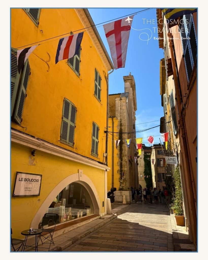Flags line a street of yellow houses in Saint-Tropez, decorated for the Fête de la Bravade celebration.