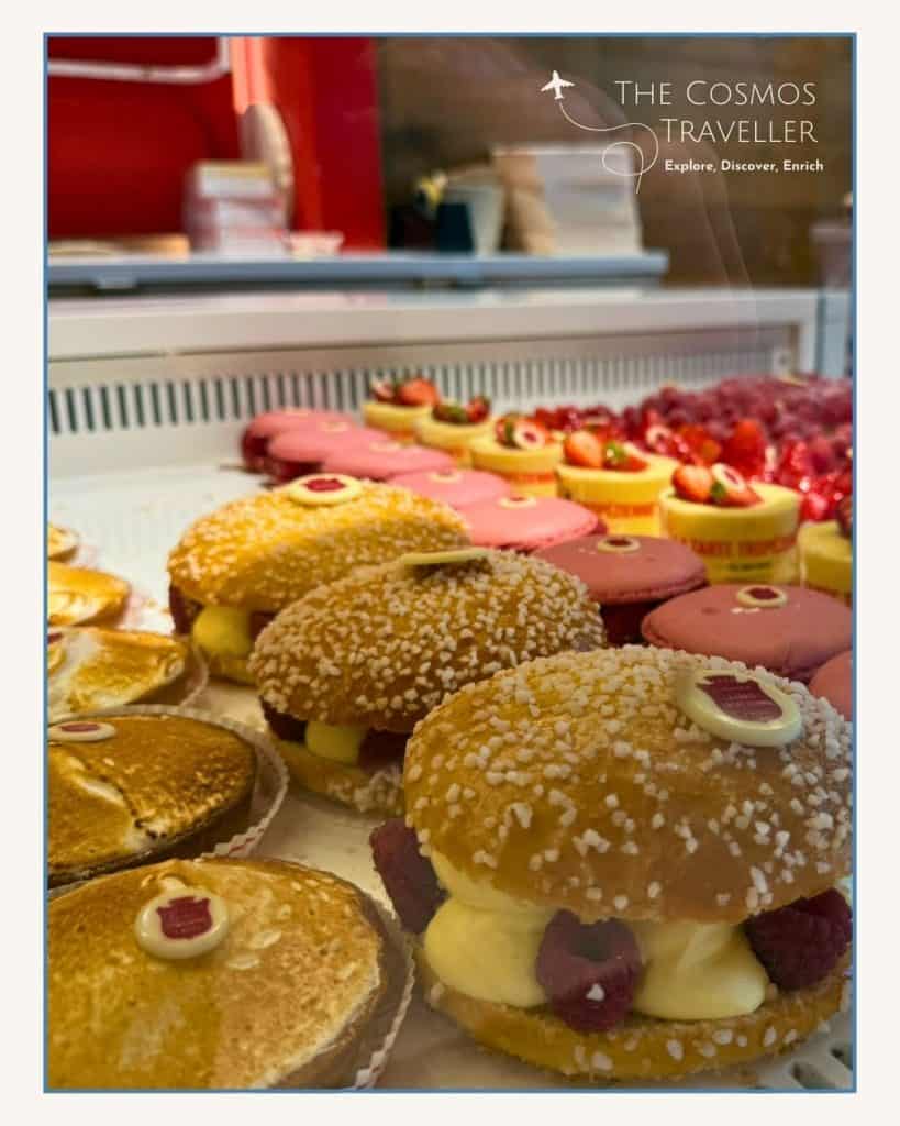 A window display of the iconic Tarte Tropézienne, showcasing the golden brioche filled with creamy custard.