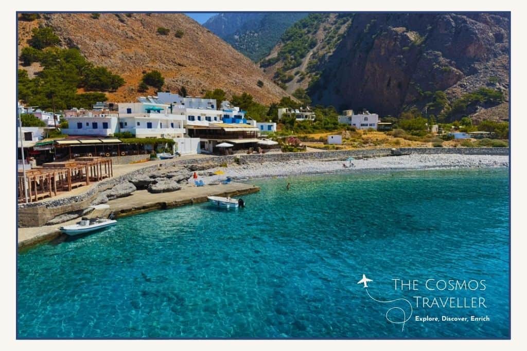 Crystal clear waters at Agia Roumeli with the village and end of the Samaria Gorge visible in the distance.