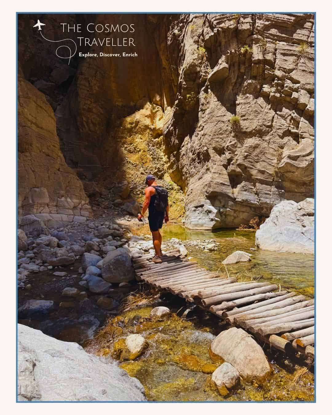 Hiker crossing a wooden bridge over water in the riverbed of the Samaria Gorge.