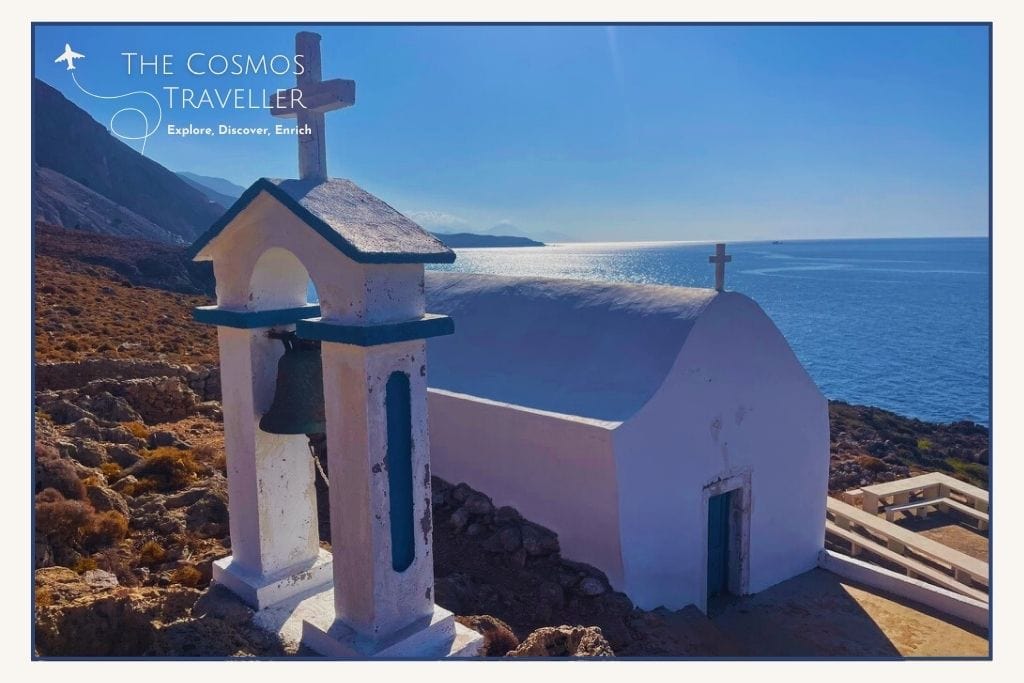 A whitewashed Greek church reflects the blue ocean in the bright sunlight.