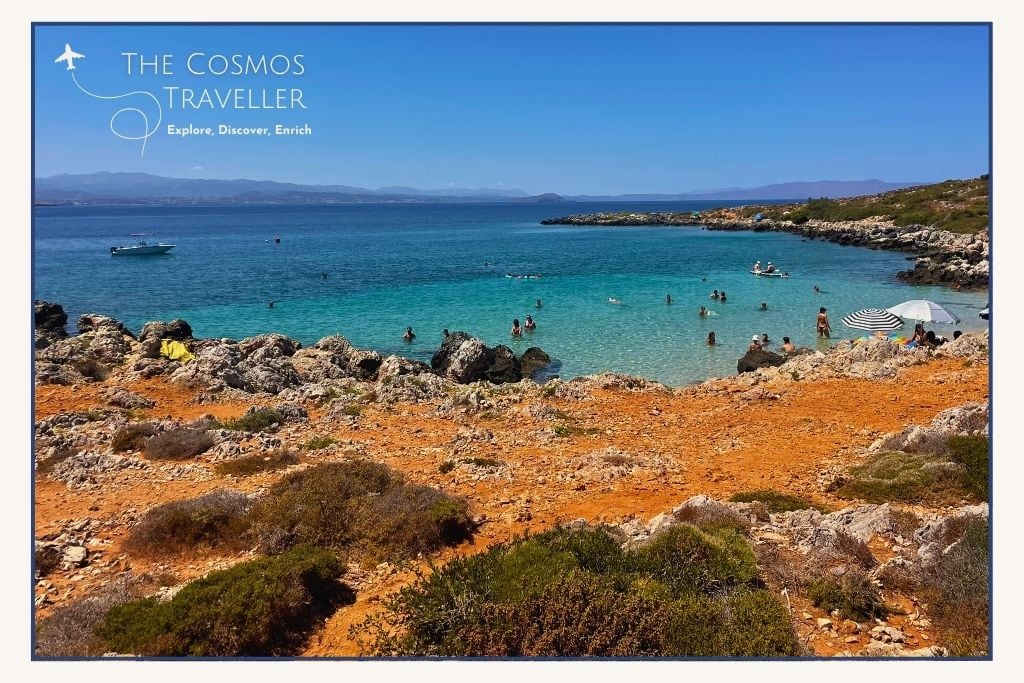 Secluded cove of Macherida Beach in Crete, where red sand contrasts with turquoise and deep blue water.