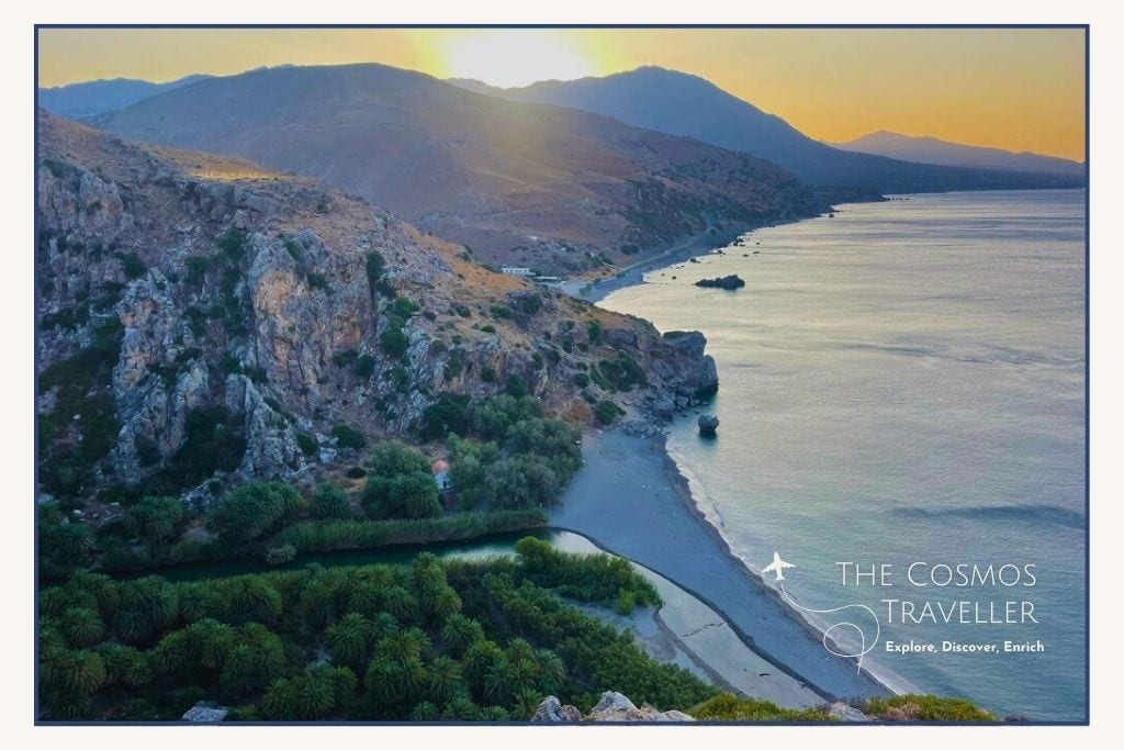 Drone view of Preveli Beach in Crete at sunrise, with palm trees lining the river and beach below.
