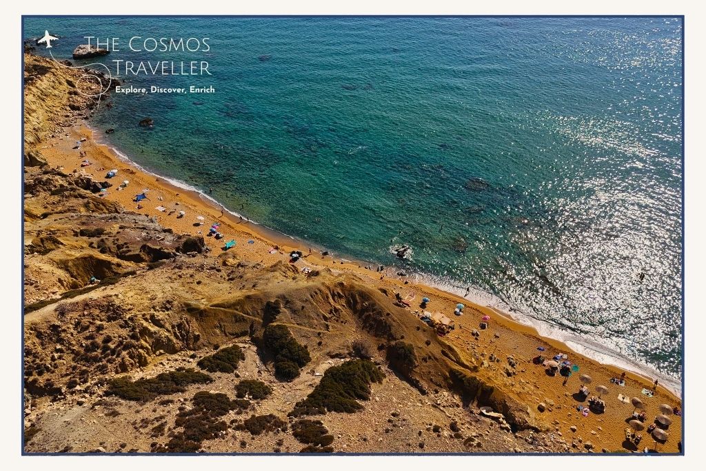 Drone view of Red Beach in Crete with red sand and turquoise sea cutting diagonally across the coastal landscape