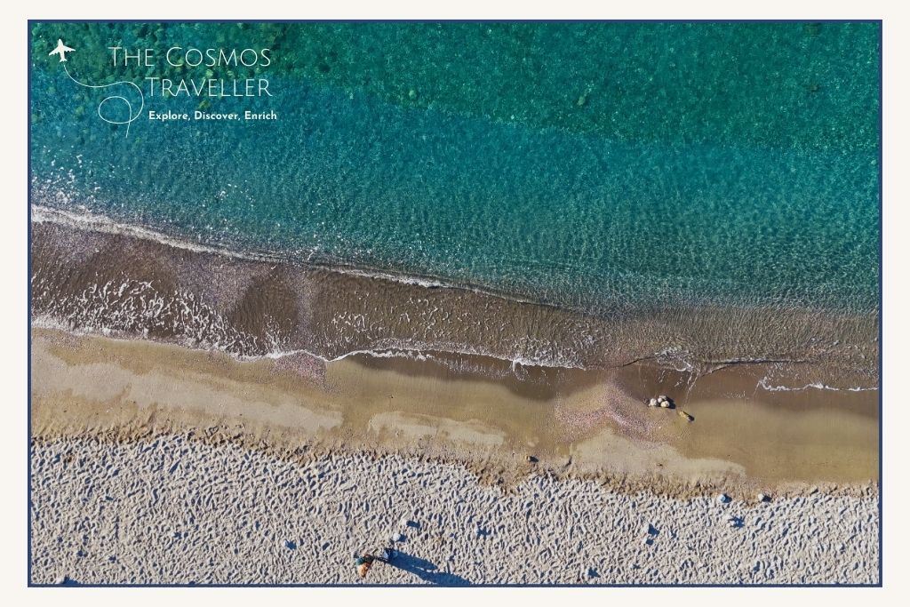 Aerial drone shot of Paralia Agias Irinas — turquoise water and narrow pebbly beach near Plakias.