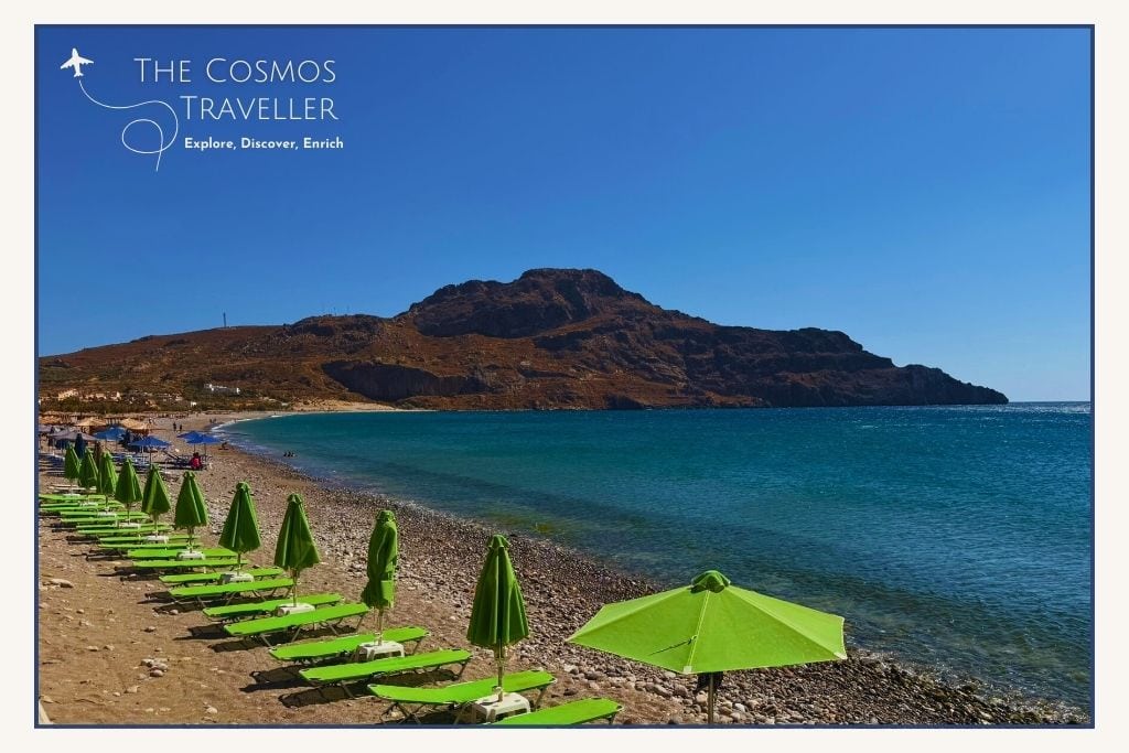 View of Plakias Main Beach with organised umbrellas, shallow bay waters, and the resort backdrop.