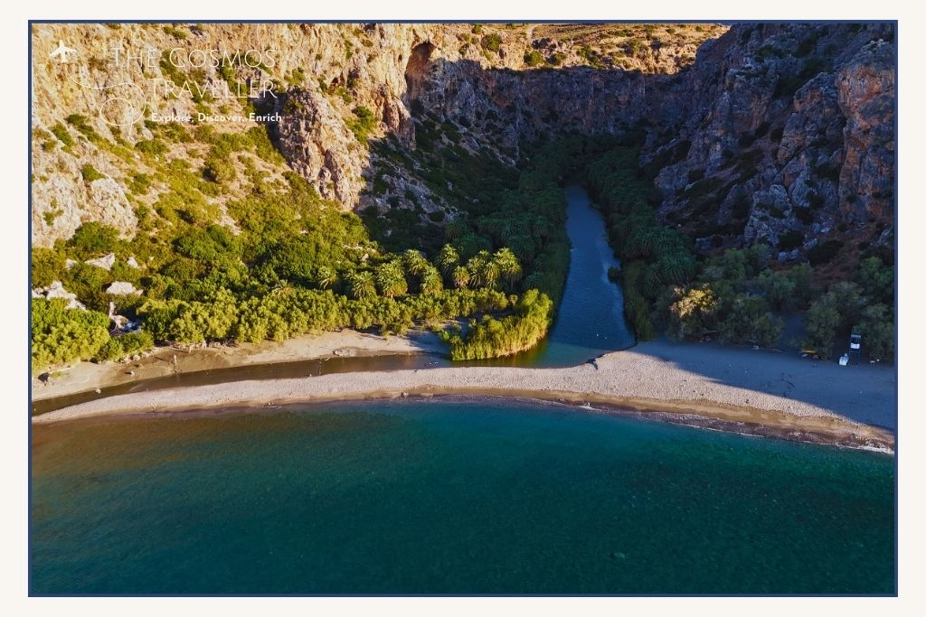 Drone shot of Preveli Beach showing the palm forest, sandy bay, and river lagoon flowing into the sea — a highlight near Plakias.