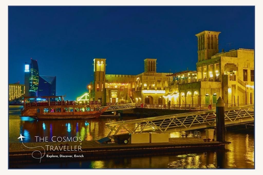 Historic Al Seef waterfront glowing at night with lantern-lit walkways and reflections on Dubai Creek.