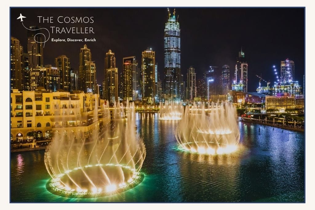 Dubai Fountain show in full motion with colourful lights and water jets set against the Burj Khalifa.