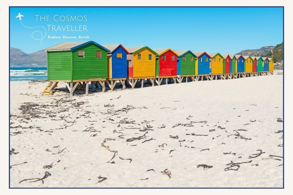 Colourful beach huts and surfers at Muizenberg Beach in Cape Town.
