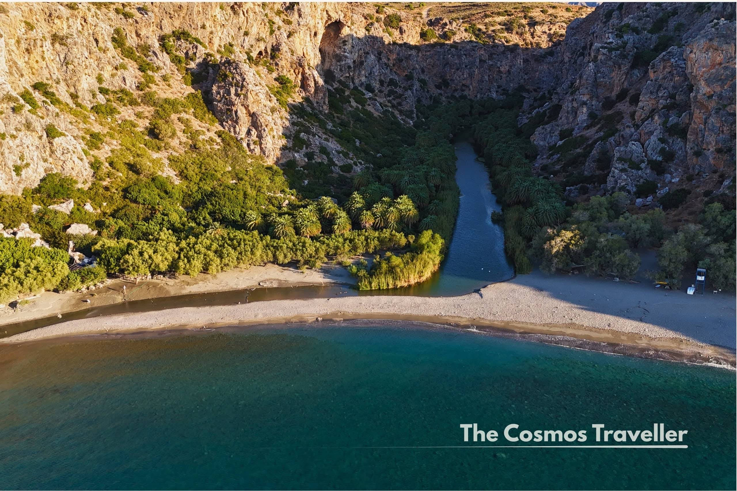 Aerial drone view of Preveli Beach's palm forest and lagoon meeting the sea, Crete